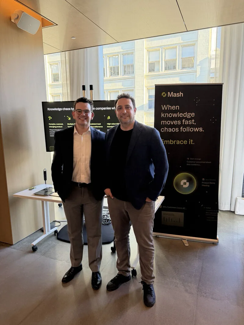 Two team members in front of the Mash banner at DemoFest SF