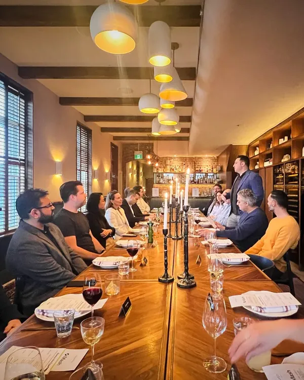 The team and guests at a long candle-lit dinner table