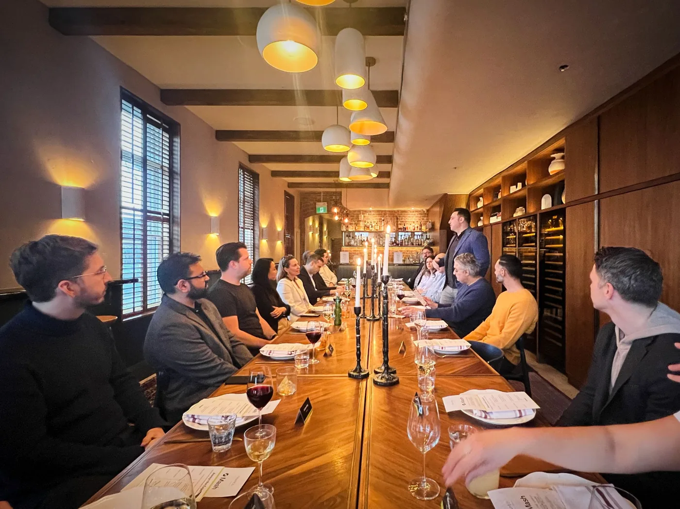 The team and guests at a long candle-lit dinner table